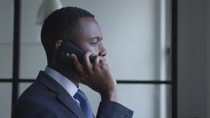 The man talks on the phone in front of the window