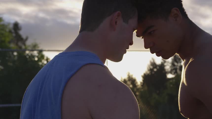 Two athletes get into an argument on an outdoor athletic field at sunset