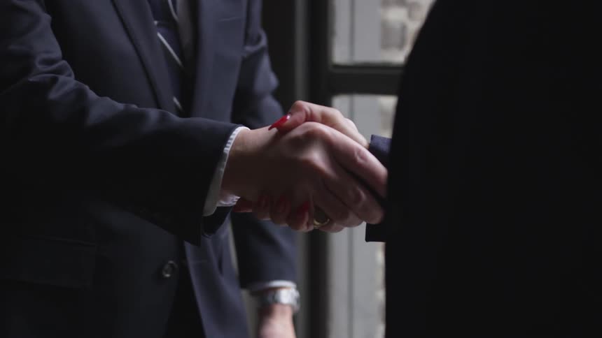 Two business professionals shake hands in an office