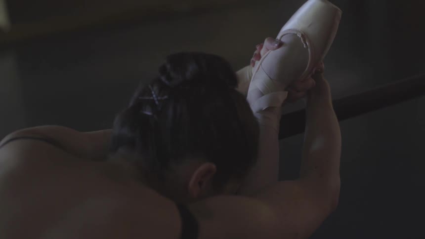 A ballerina stretches in a dance studio