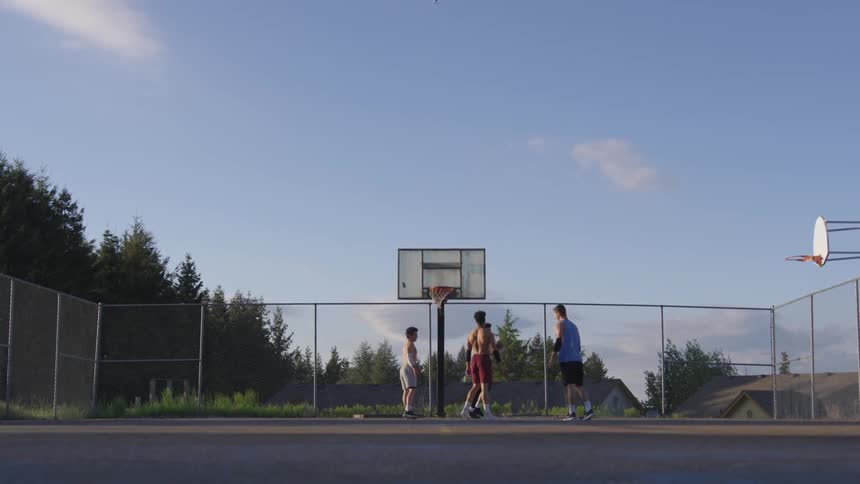 Men play basketball on an outdoor court