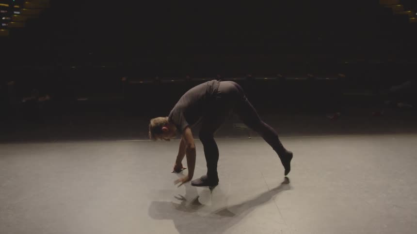 A male dancer stretches on stage