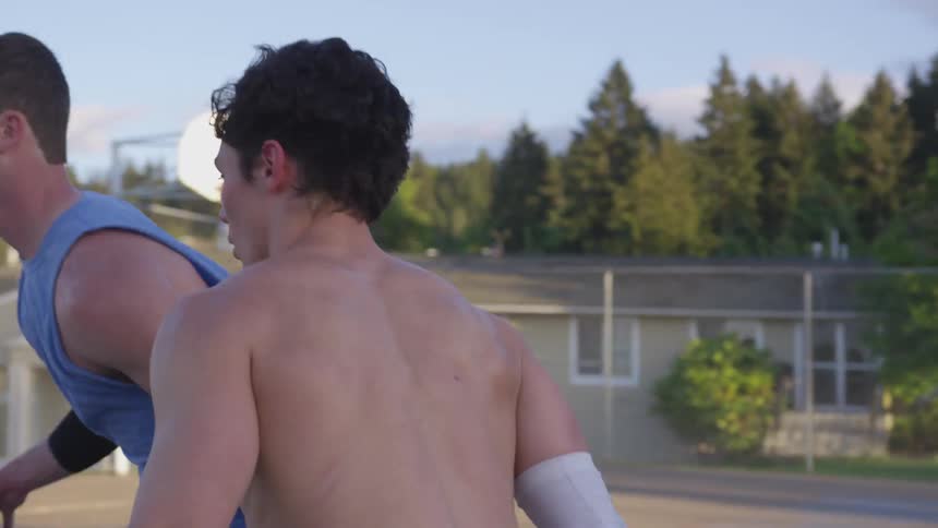Two teenagers play basketball on an outside court