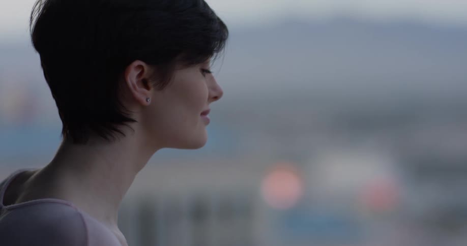 Woman leans against the balcony looking the city below