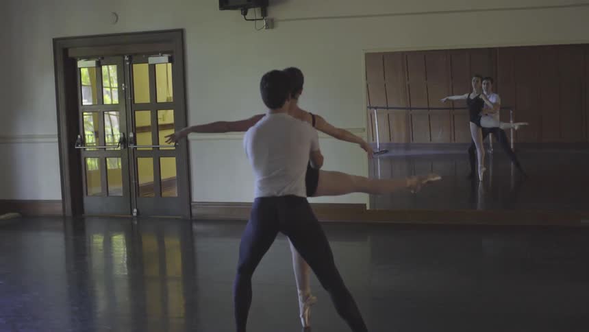 A ballerina spins as a man stands by