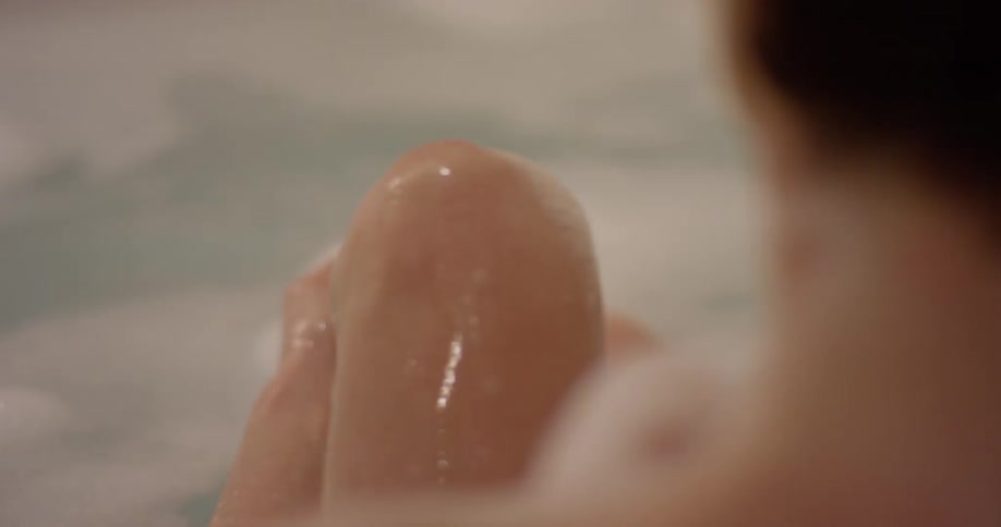 A woman washes her leg while taking a bath