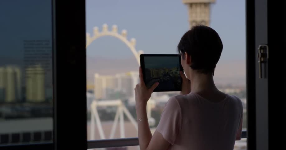 A woman takes a picture of las vegas from a hotel balcony