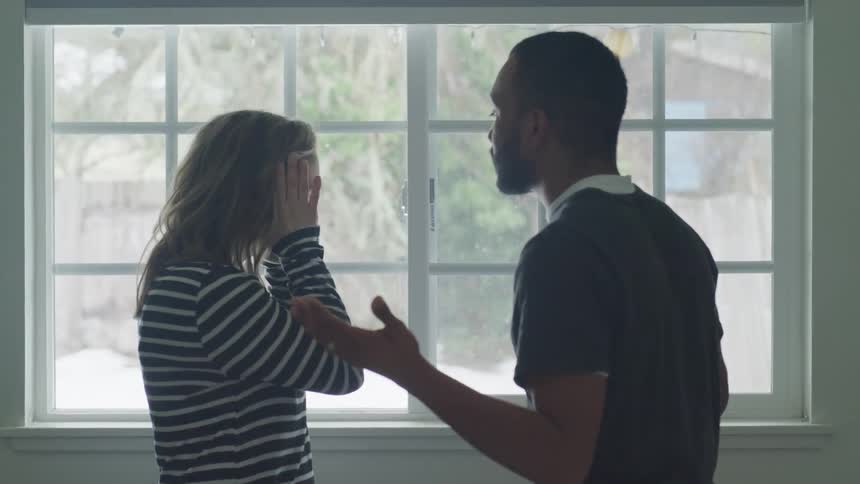 Man consoles a woman who is covering her hands with her faces