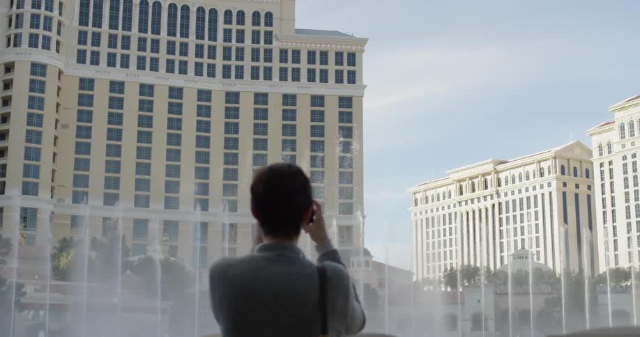 Woman takes pictures of fountains in front of a hotel