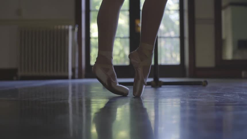 Woman practices ballet moves near the patio doors