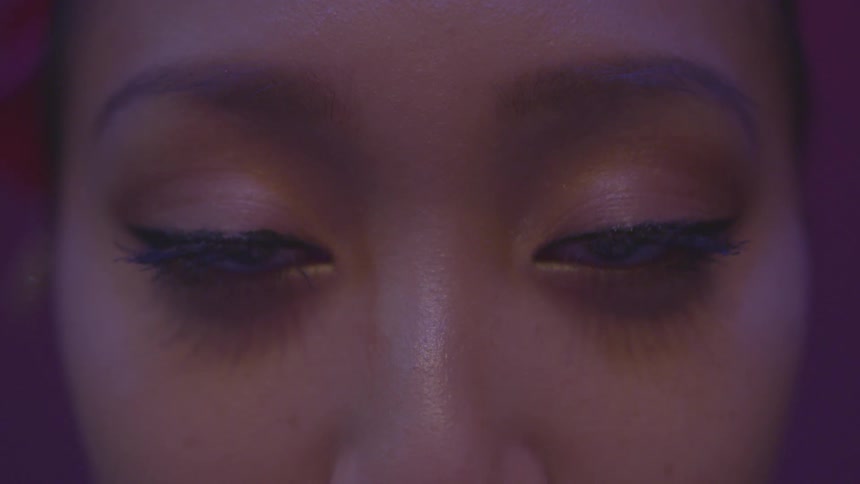 A woman looking straight ahead blinks