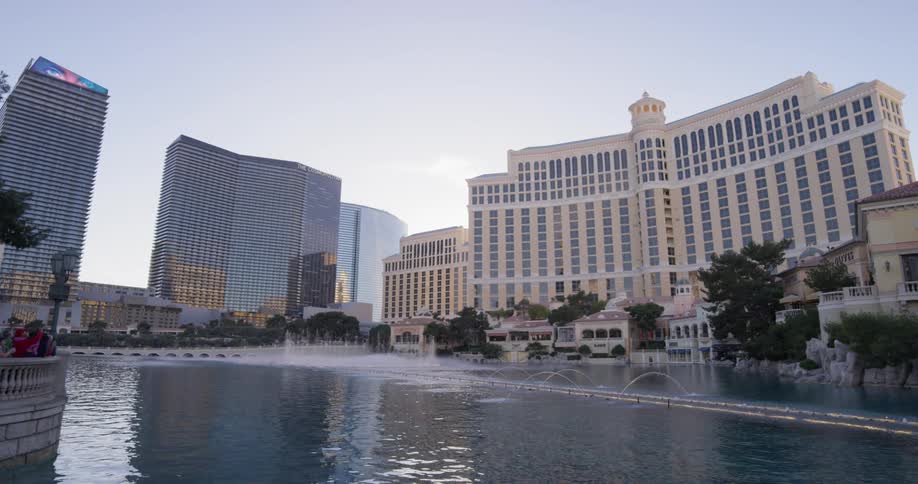 Fountains in a pool splash upwards in front of a large hotel