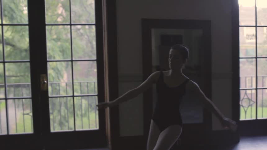 A ballerina leaps in a dance studio