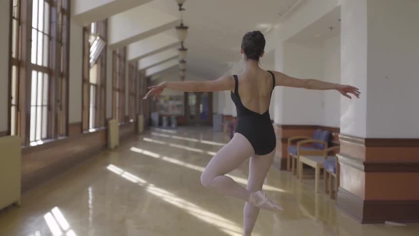 A ballerina dances down a hallway on a sunny day