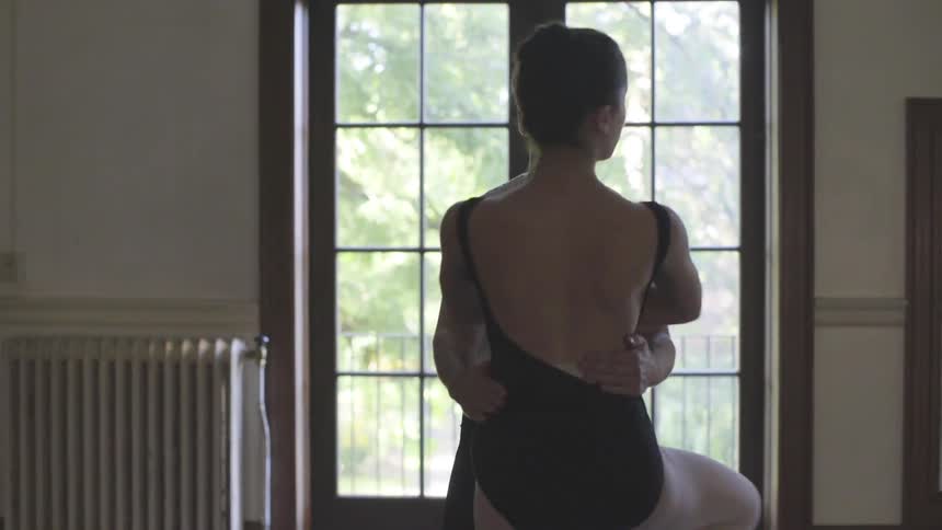 A man stands behind a woman doing ballet moves and turns