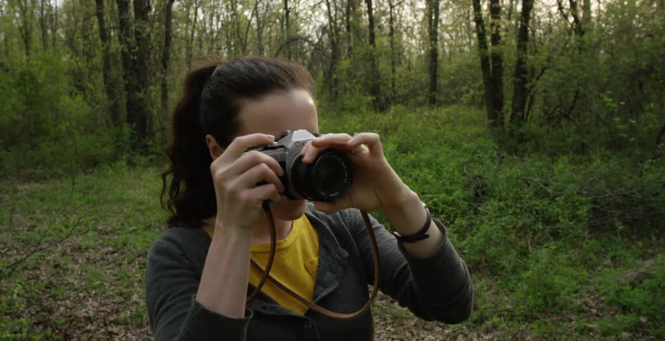 Woman pauses to take a picture in a forest