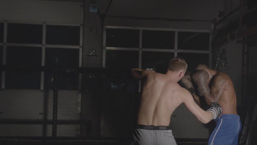 Two men boxing with each other in gym at night