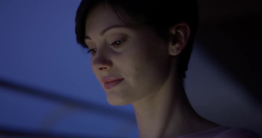 A woman looks around and smiles at night