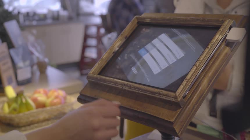 A cashier tilts the order screen back towards her