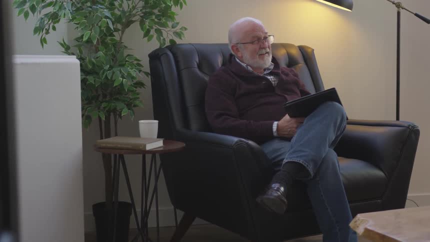 A man smiles with a pad in the chair