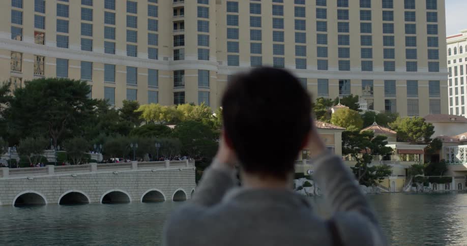 Woman takes a photo of the buildings near the lake