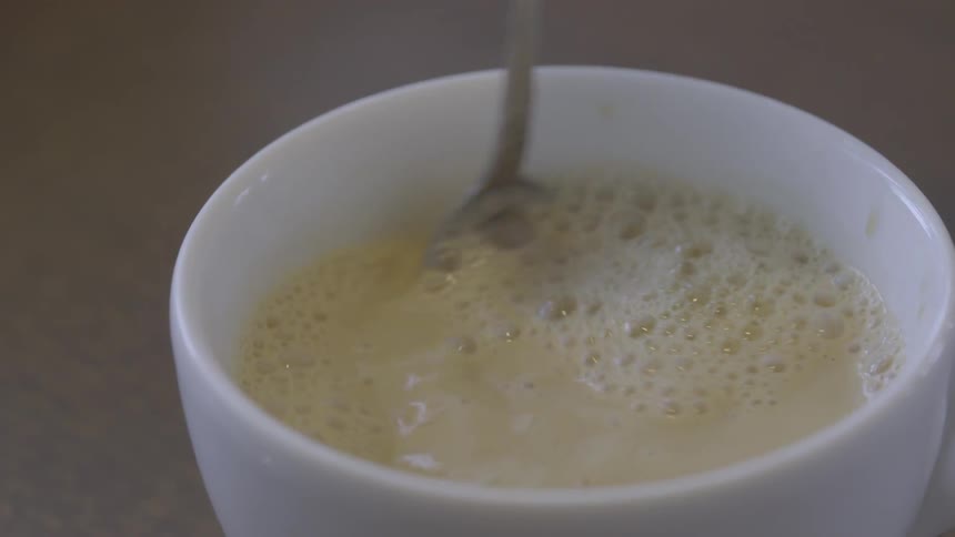 The person mixes their beverage