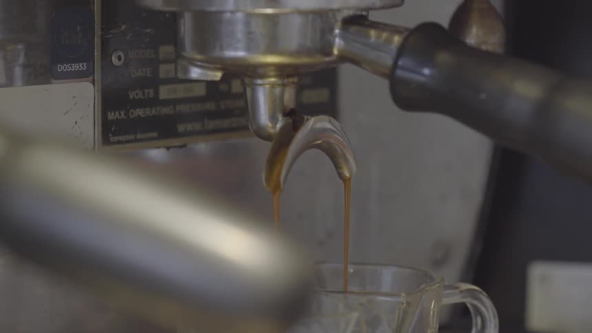 An espresso machine in a shop is brewing coffee