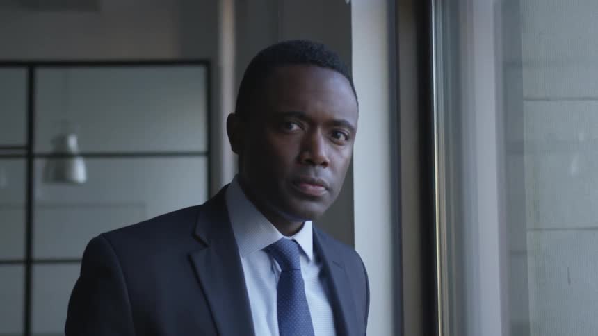 A businessman stands next to a window