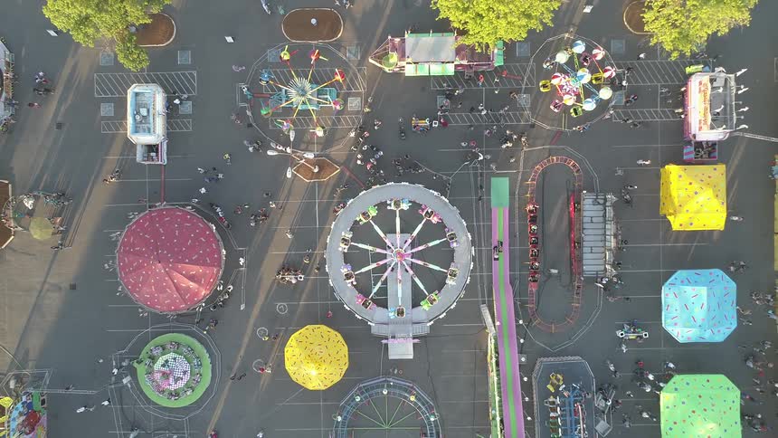 Fairgoers wander around a fairgrounds in daylight