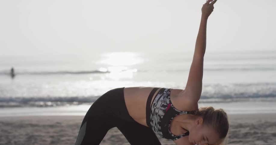 A woman does yoga on a beach