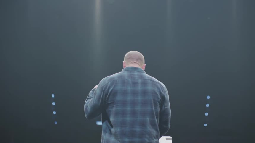A man on a stage stands at a podium and gestures