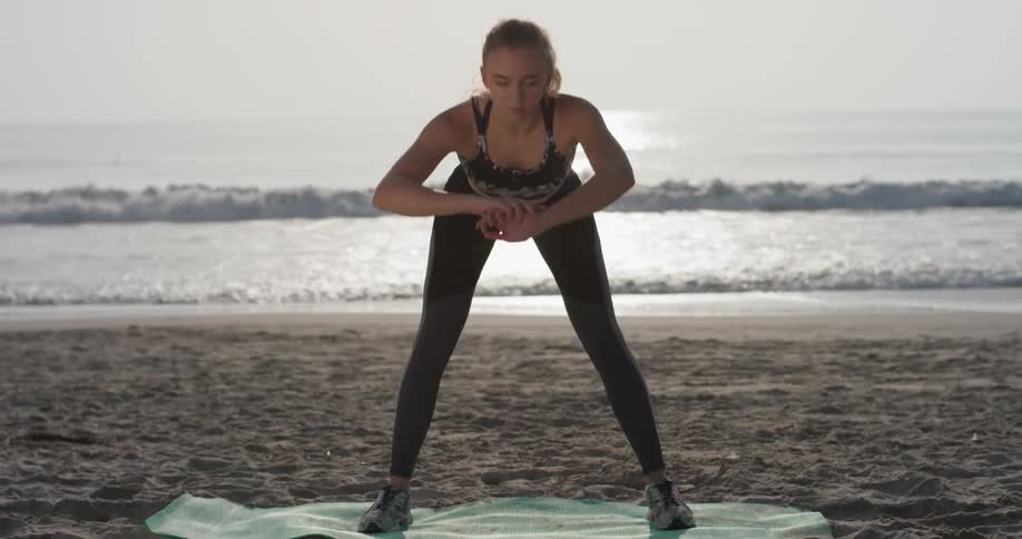 A woman bends and stretches on the beach