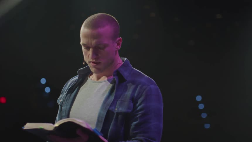A man reads from a book on stage