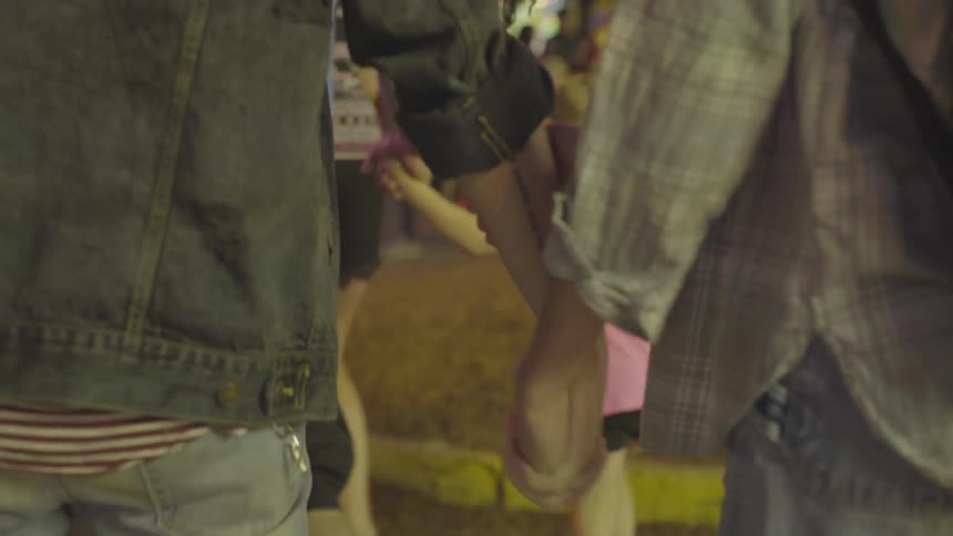 A man and woman hold hands as they walk