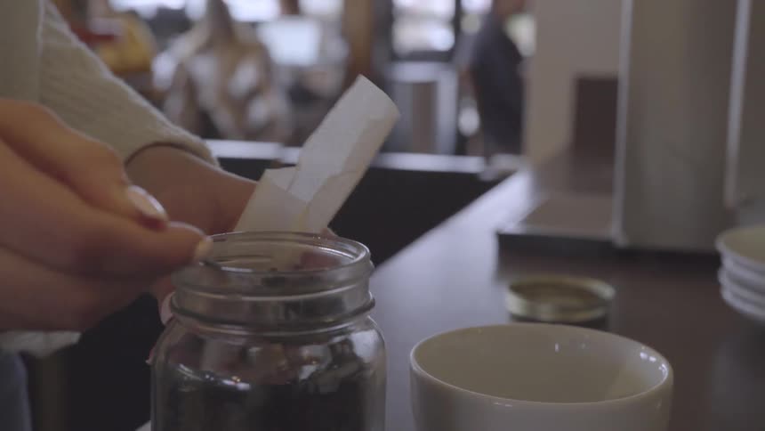 The person scoops coffee into a bag