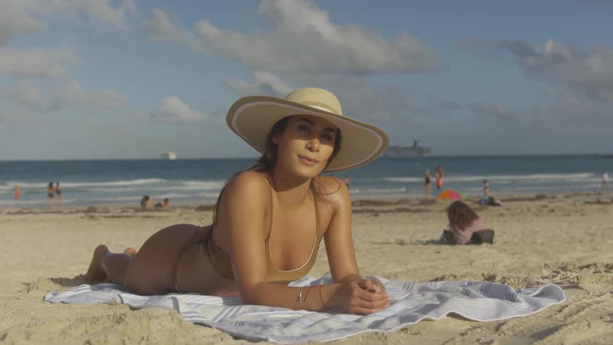 A woman lays on the sand smiling