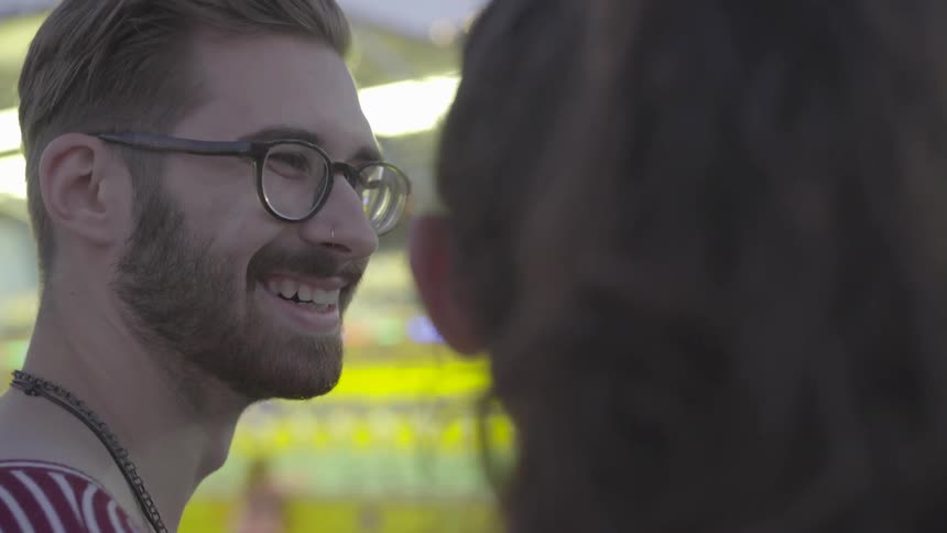 A man smiles at a woman at a carnival