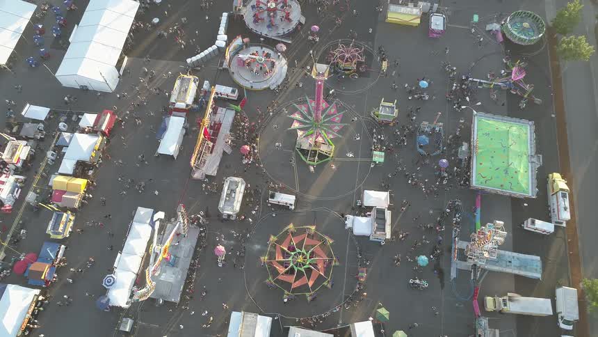 People walk around rides at the carnival