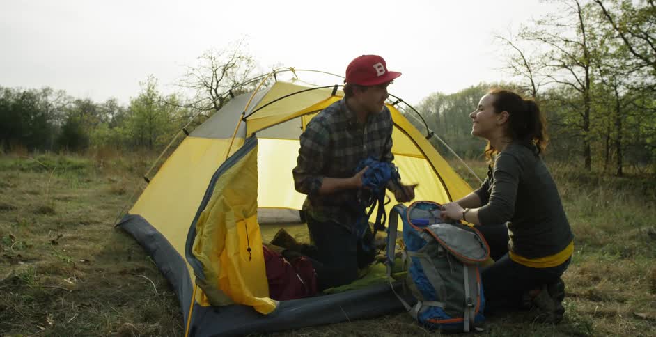 A man and woman kneel by a tent