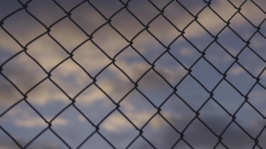 Clouds in the sky behind a chain link fence