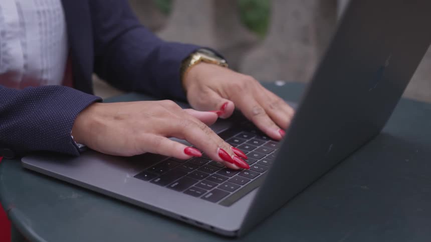 A woman is typing on her laptop keyboard