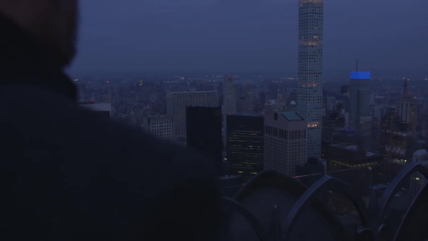 A man stands outside in a city at night