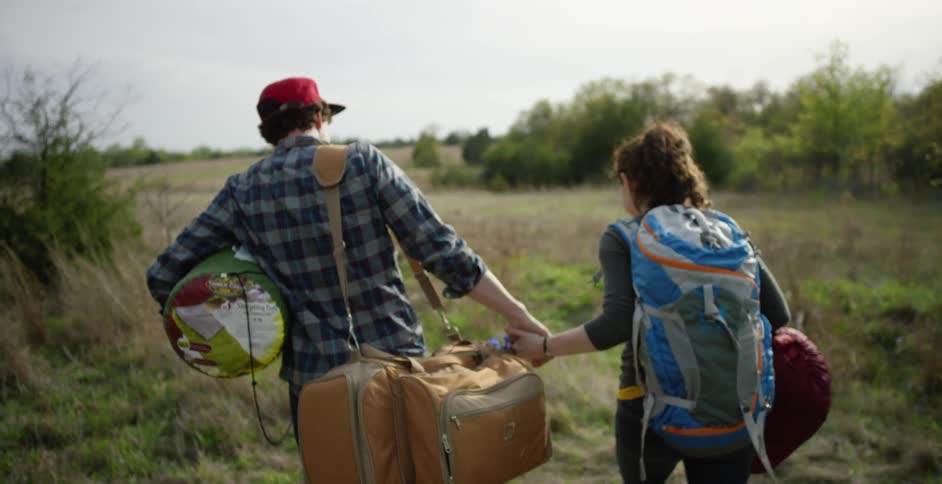 A man and woman carrying supplies to go camping
