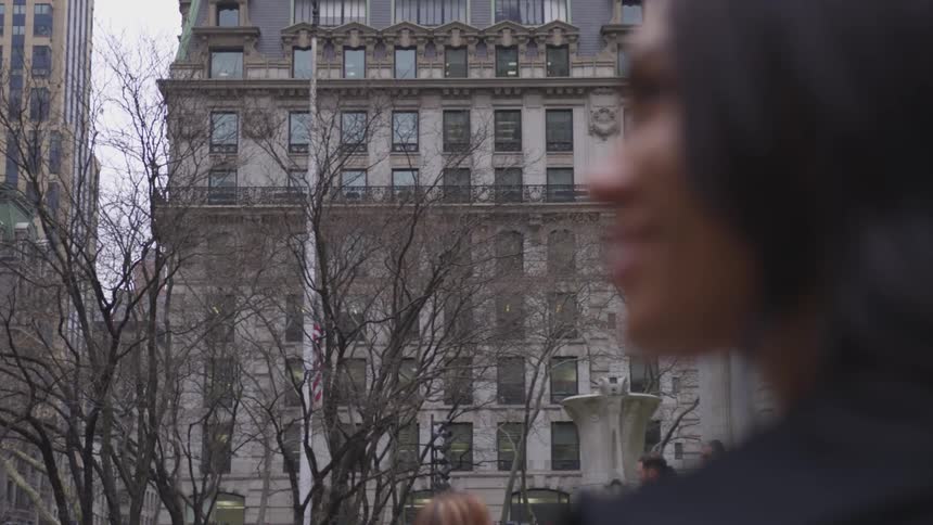 A woman smiles outside in a city