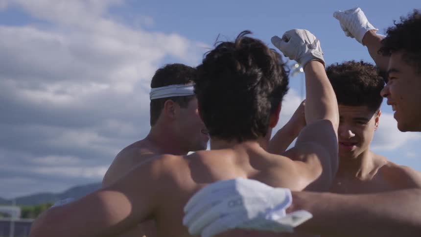 Athletes huddle on an outdoor athletic field