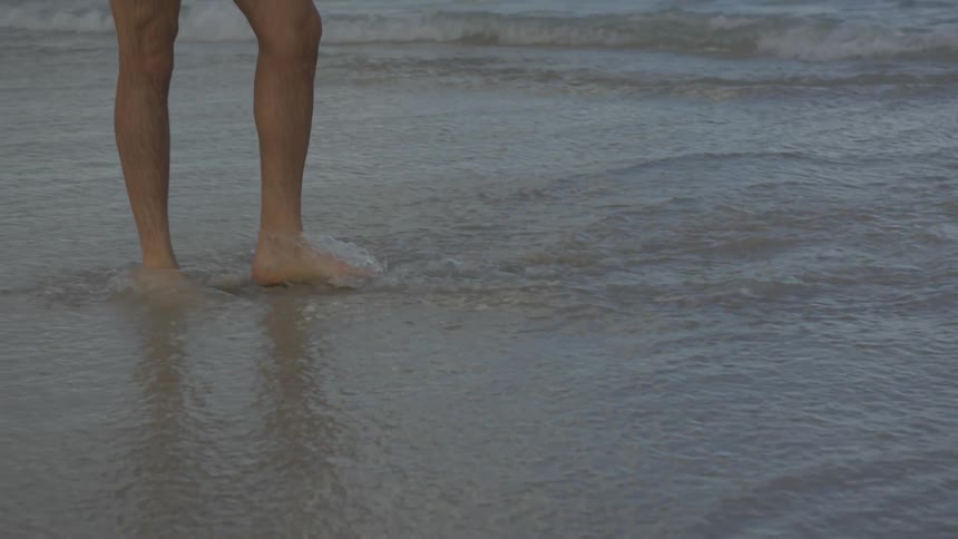 A person walks in the water on the beach