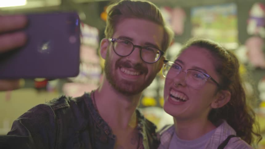 A man and woman smile as he takes a selfie