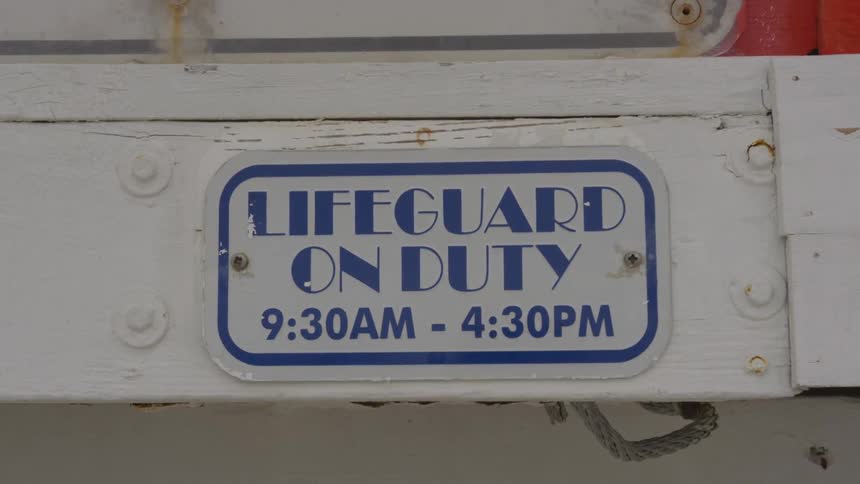 The sign shows the hours of the lifeguard stand