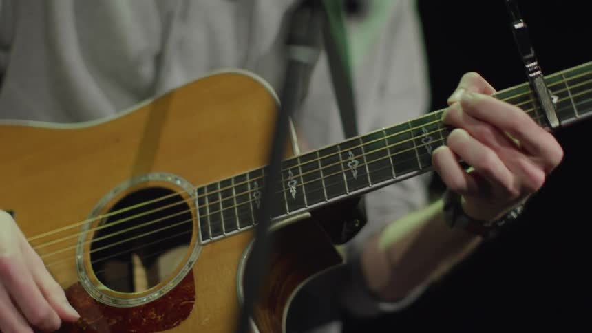 Person plays acoustic guitar on stage