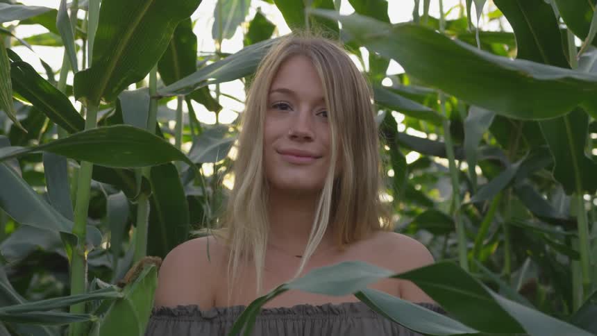 Woman stands outside surrounded by tall plants